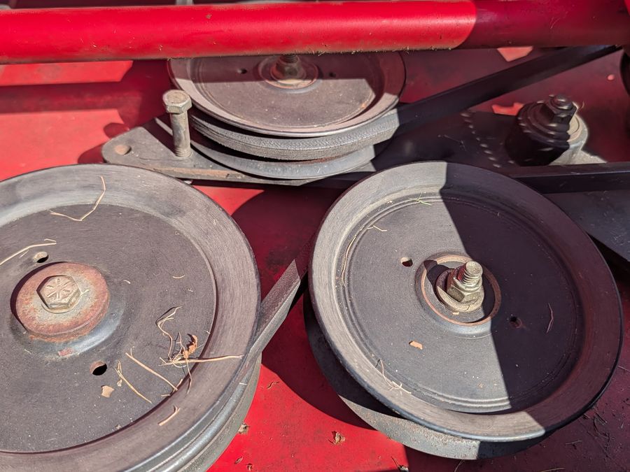 Underside of a mower deck showing pulleys and belt routing